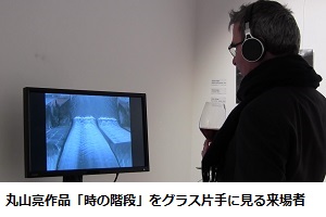 丸山亮作品「時の階段」をグラス片手に見る来場者