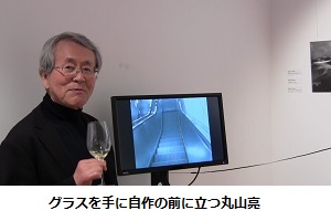 グラスを手に自作の前に立つ丸山亮